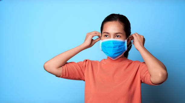 istock Female wearing protective mask virus and posing against blue background. 1216371905
