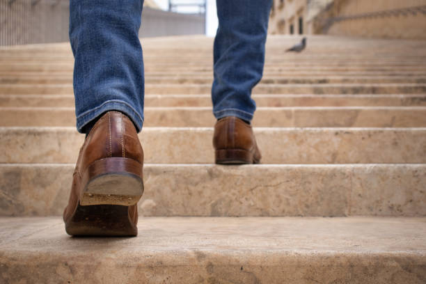 A young man climbing up along large endless stair alone