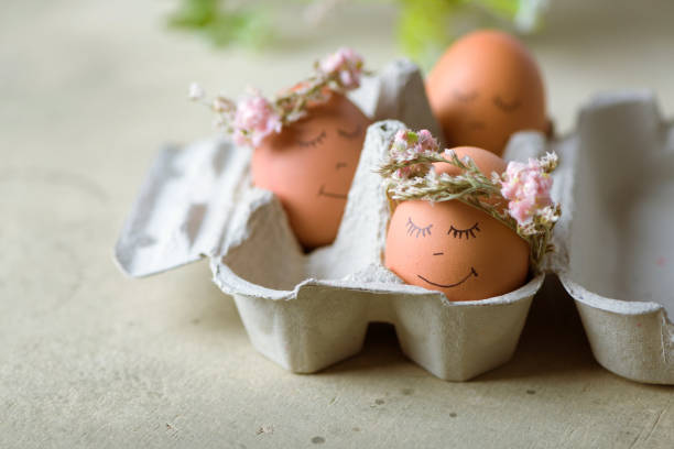 istock Natural easter eggs with funny painted face and sweet flower wreath 1216380966