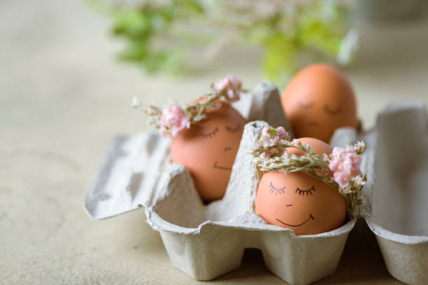 istock Natural easter eggs with funny painted face and sweet flower wreath 1216381221