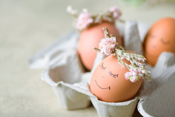 istock Natural easter eggs with funny painted face and sweet flower wreath 1216381309