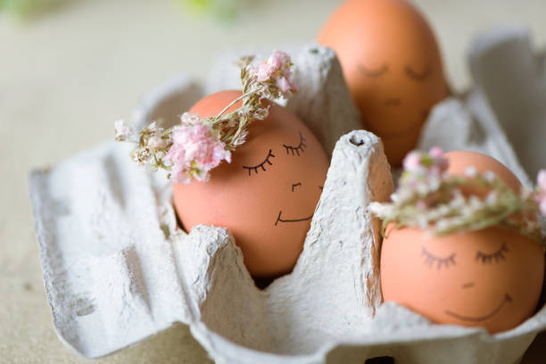 istock Natural easter eggs with funny painted face and sweet flower wreath 1216383147
