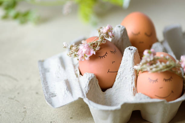 istock Natural easter eggs with funny painted face and sweet flower wreath 1216383193