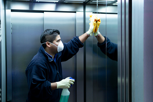 Coronavirus. personal de limpieza desinfectando el ascensor para evitar el contagio photo