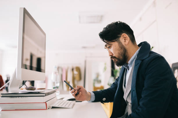 Man sitting behind the desk, looking at smartphone