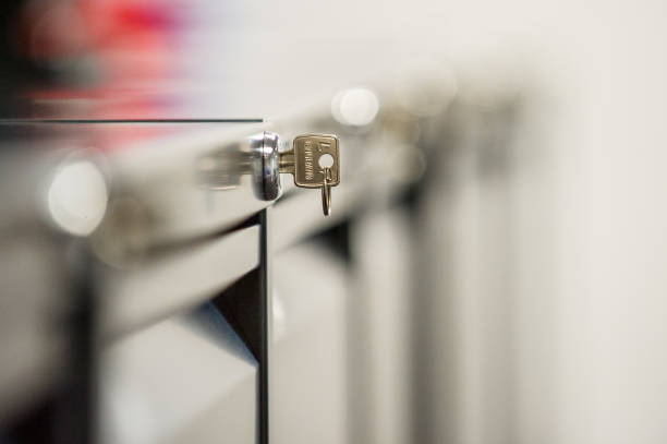 Close up of key in lock of filing cabinet with copy space around Close up of key in lock of filing cabinet in centre of photo with out of focus line of filing cabinets reaching to the background and lots of white space around filing cabinet stock pictures, royalty-free photos & images