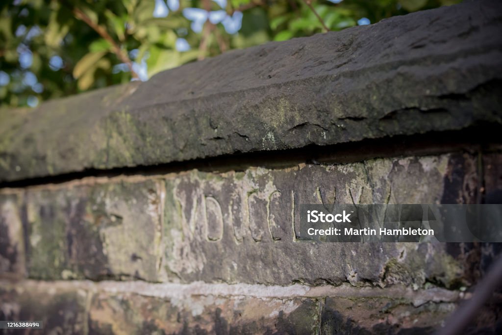 Close up of Roman numerals carved into old stone brick Part of a stone wall showing Roman numerals carved into the face of one weathered brick Carving - Craft Product Stock Photo