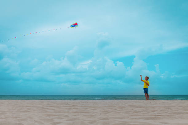 istock happy boy flying a kite on tropical beach 1216388664