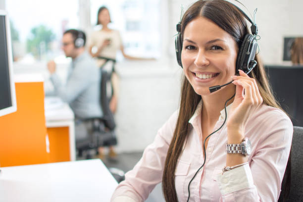 istock Friendly female helpline operator with headphones in call center 1216391642