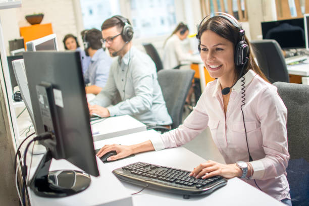 friendly female operator consulting client on hotline in call center - call center imagens e fotografias de stock