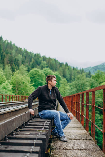 istock A man in jeans sits on a railway track. 1216391869