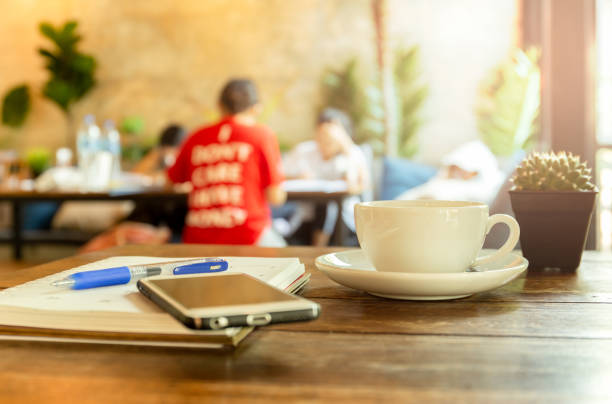 istock Cup of coffee with cell phone and book, pen on the table. 1216392199