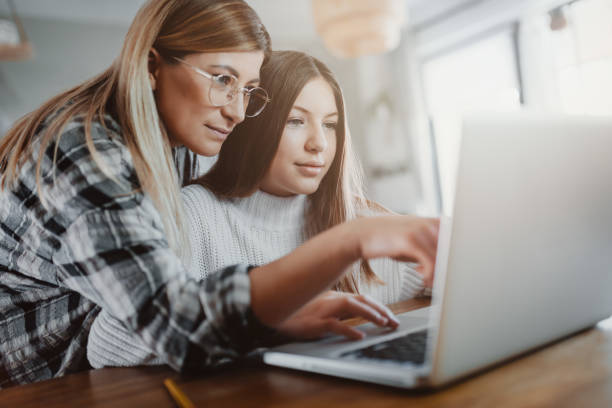Mother and child doing homeschooling, e-learning at home