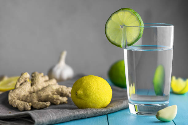 cup of water with lemon, garlic and ginger on blue wooden table. prevention of colds. increased immunity - ginger tea cup cold and flu tea imagens e fotografias de stock