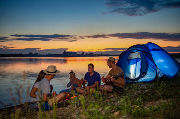 istock Friends sitting around campfire while camping on lakeshore at sunset 1216397673