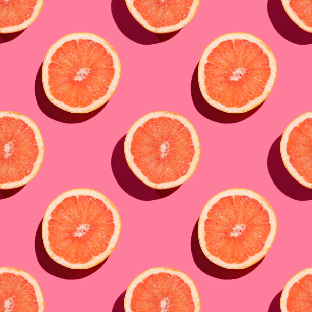 istock Seamless pattern of halves of grapefruit on pink background. 1216397906