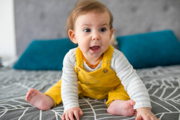 istock Cute baby sitting on a bed, smiling 1216398787