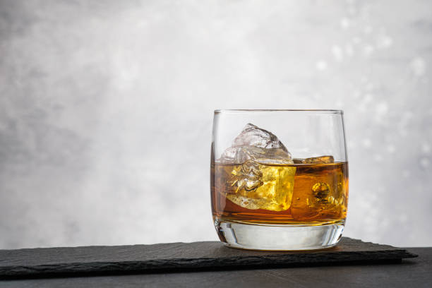 whisky de plan rapproché avec des glaçons sur le fond gris - shot glass glass black empty photos et images de collection