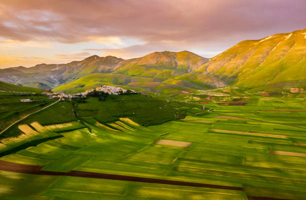 vista aerea panoramica di un paesaggio di campagna con molti campi patchwork e splendide colline verdi, castelluccio, umbria, italia - umbria foto e immagini stock