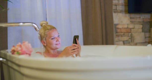 istock Woman using mobile phone in bathtub 1216402198