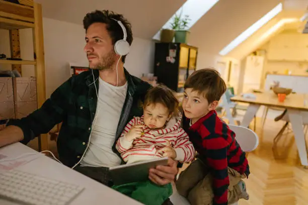 Photo of a man working from home, with his sons as a company