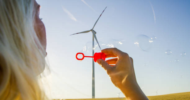 istock Blond woman blowing soap bubbles in field. 1216403161