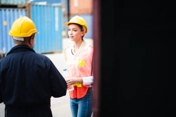 istock Young Caucasian man and woman worker standing and discussion work about loading freight Containers at commercial shipping dock felling happy. Cargo freight ship import export concept 1216403163