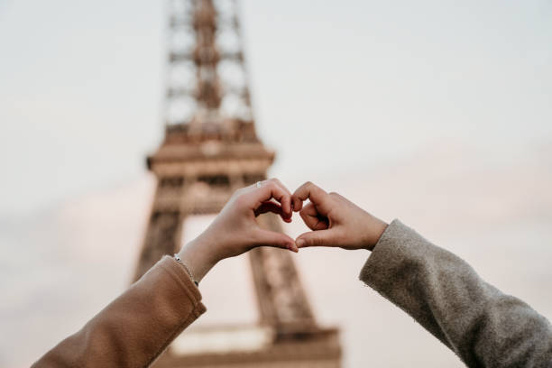 Young couple making heart symbol over eiffel tower stock photo