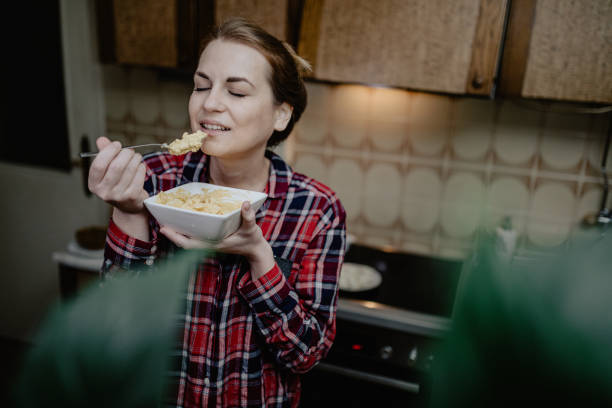 istock Woman eating breakfast from a bowl in the kitchen 1216406637
