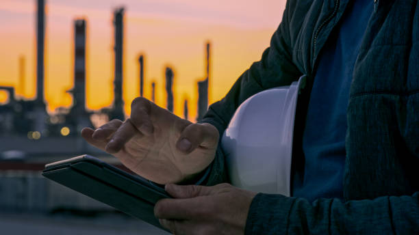 close-up of engineer using tablet near oil refinery. - chemical plant refinery industry pipe imagens e fotografias de stock