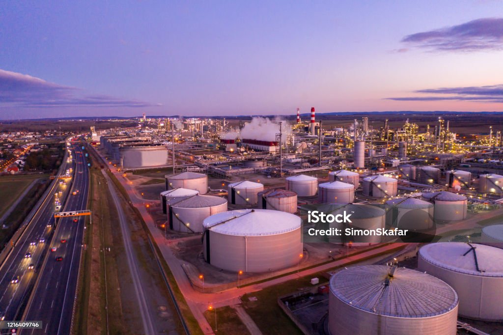 Aerial view of oil refinery at sunset. Drone point of view shot of an oil refinery under a moody sky at sunset. Oil Refinery Stock Photo