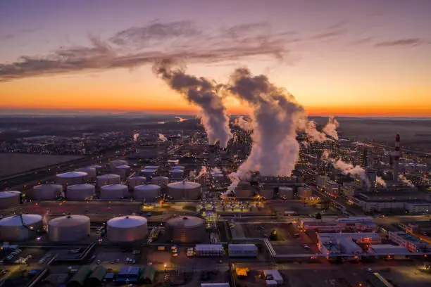 Drone point of view shot of an oil refinery under a moody sky at sunset.