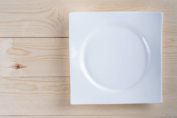 istock Flat lay above empty white plate on the wooden boards table background 1216411789
