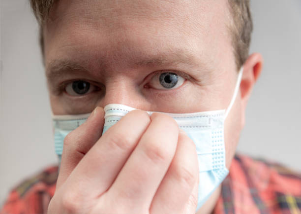 istock Man puts on a medical face mask 1216412373