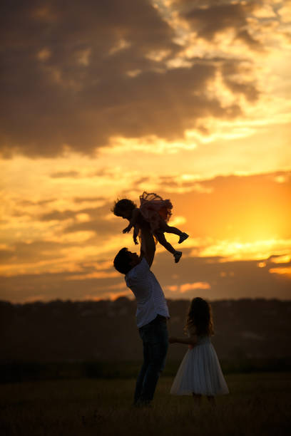 istock daddy throws up daughter in field at sunset. the 1216412615
