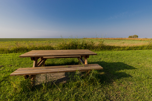 a bench with table in a meadow with blue sky on the horizon