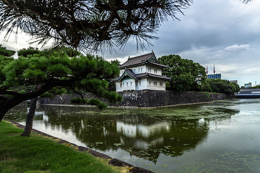 Exterior walls and tower of Tokyo Imperial Palace reflected in water. Tokyo, Japan, August 2019