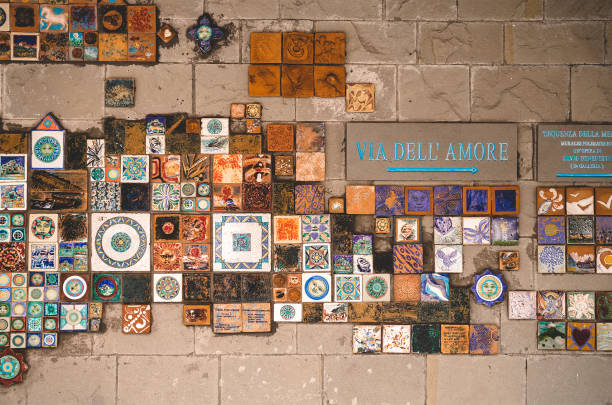 Colorful tiles on the brick wall showing direction to Via Dell'Amore, a pedestrian Path Of Love overlooking the sea in Cinque Terre, Italy.