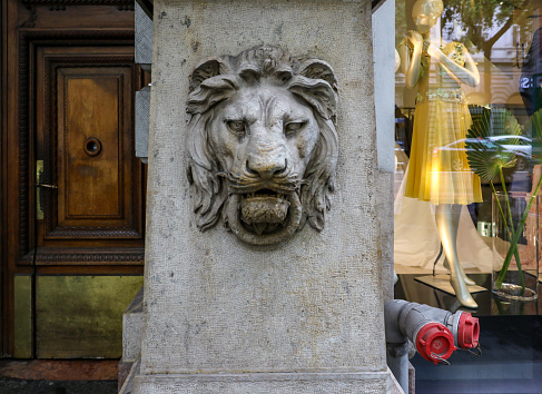 A stone sculptured lion's head with ring in its mouth on the outside of an old building in Budapest. The lion's head was used to symbolise qualities of bravery, valour, strength, fierceness & gravitas