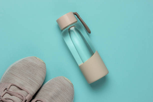 Flat lay style concept of healthy lifestyle, sport and fitness. Sports shoes for running,  bottle of water on blue pastel background. Top view stock photo