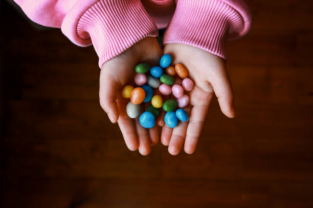 mazzo di caramelle nelle mani del bambino - gelatin dessert multi colored vibrant color celebration foto e immagini stock