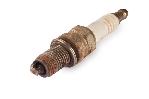 Studio shot of an old rusty spark plug cut out against a white background