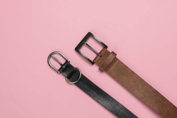 istock Two leather belts on pink pastel background close-up 1216424172