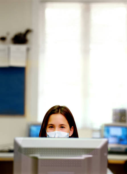 istock A little girl using a computer wearing healthcare face mask. 1216424229