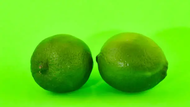 Photo of Two limes in close-up on a fluorescent green background