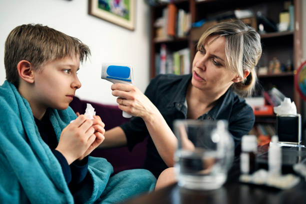 mère et fils sur l’appel vidéo de télémédecine avec le docteur - infrared thermometer photos et images de collection