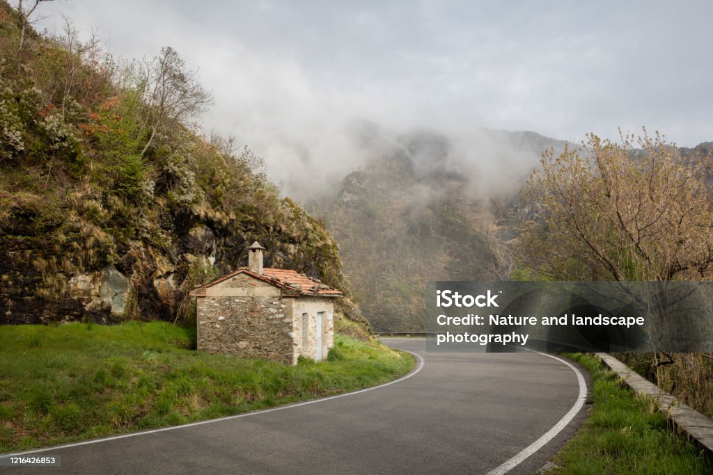 Toscany in the mist, a road going around the bend towards the mist Asphalt Stock Photo