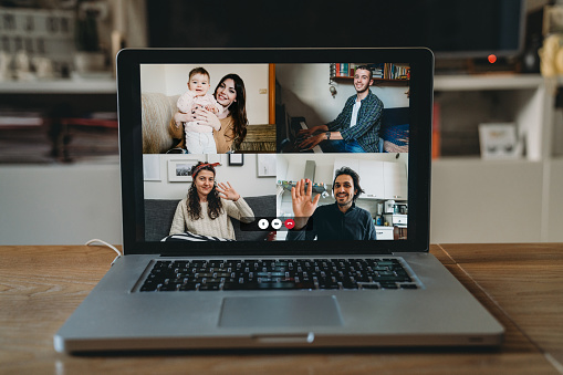 Laptop with a videoconference call on the screen. Living room. During Coronavirus Covid-19 quarantine, many people is using VoIP to connect together.