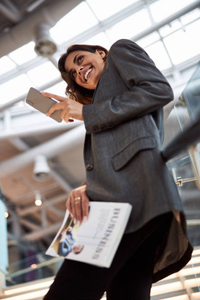 istock Charming young woman standing on stairs and using smartphone 1216428635