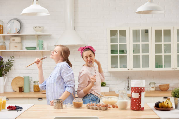 istock Two cheerful friends cook together desserts and sing 1216430210